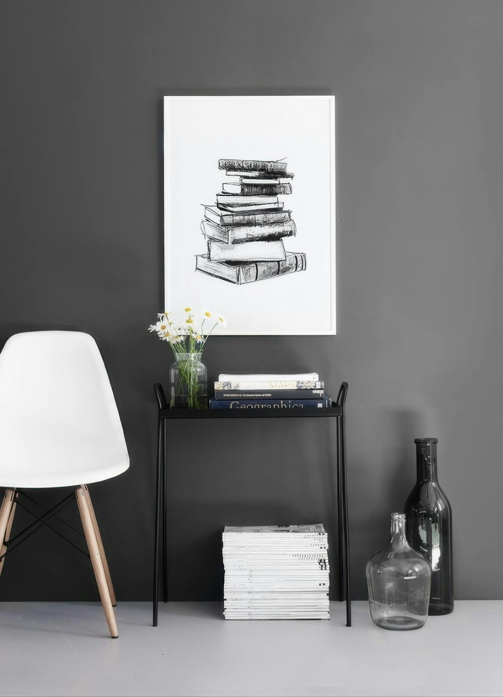 Affiche avec un dessin de pile de livres, accrochée au mur gris foncé dune pièce moderne.