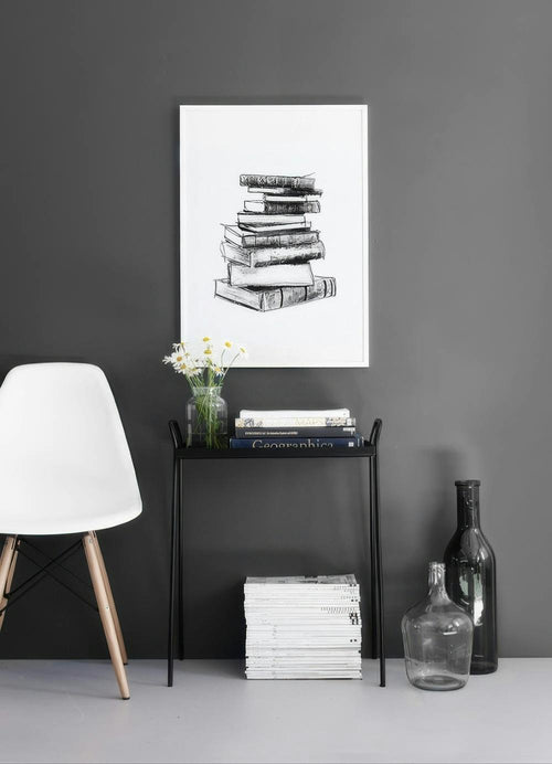 Affiche avec un dessin de pile de livres, accrochée au mur gris foncé dune pièce moderne.