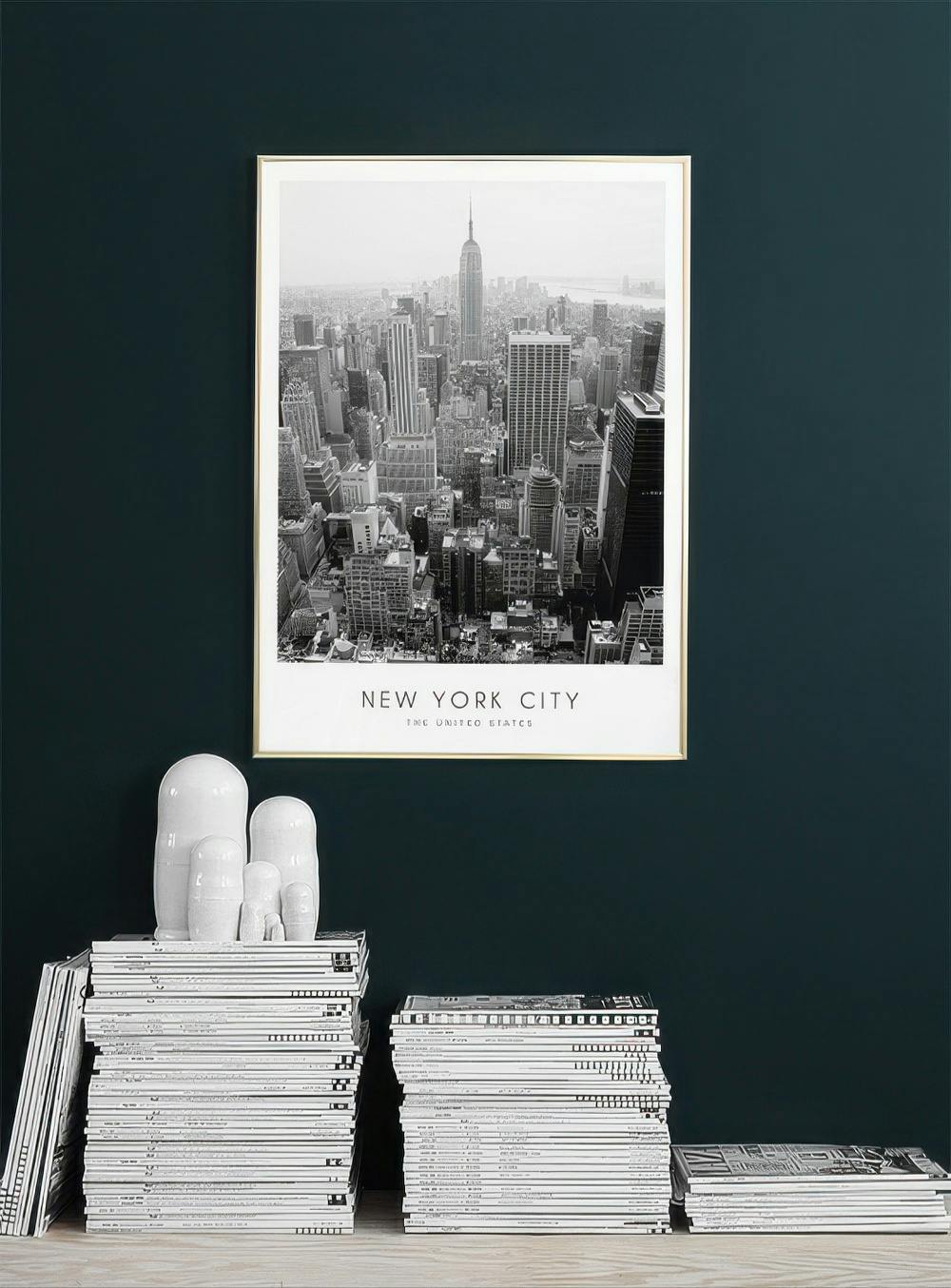 Affiche de New York en noir et blanc, avec lEmpire State Building, suspendue sur un mur foncé au-dessus de magazines.
