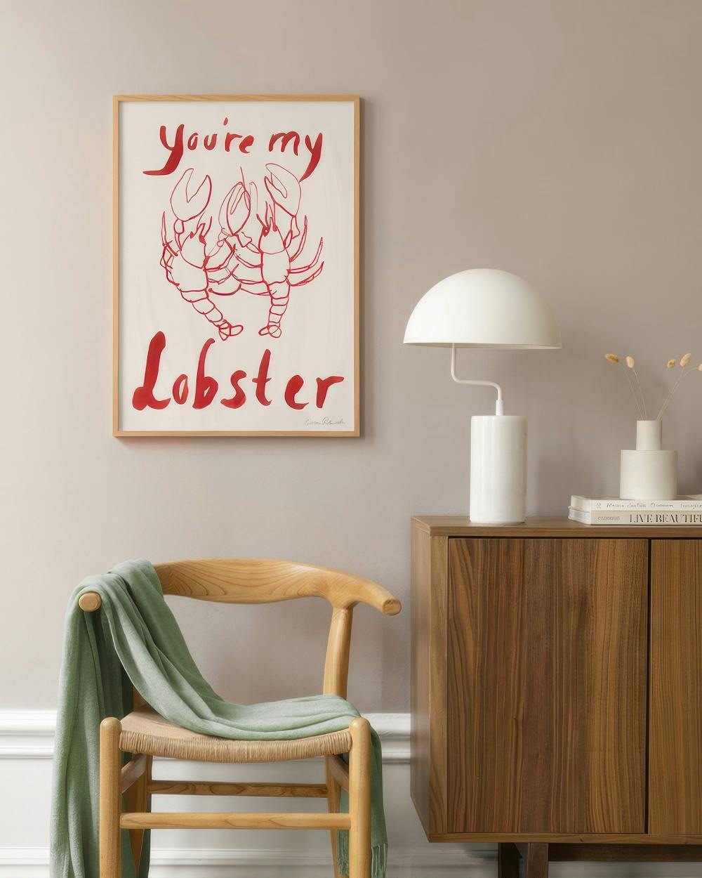 Affiche Youre my Lobster avec deux homards rouges, accrochée au-dessus dune chaise en bois dans un salon.
