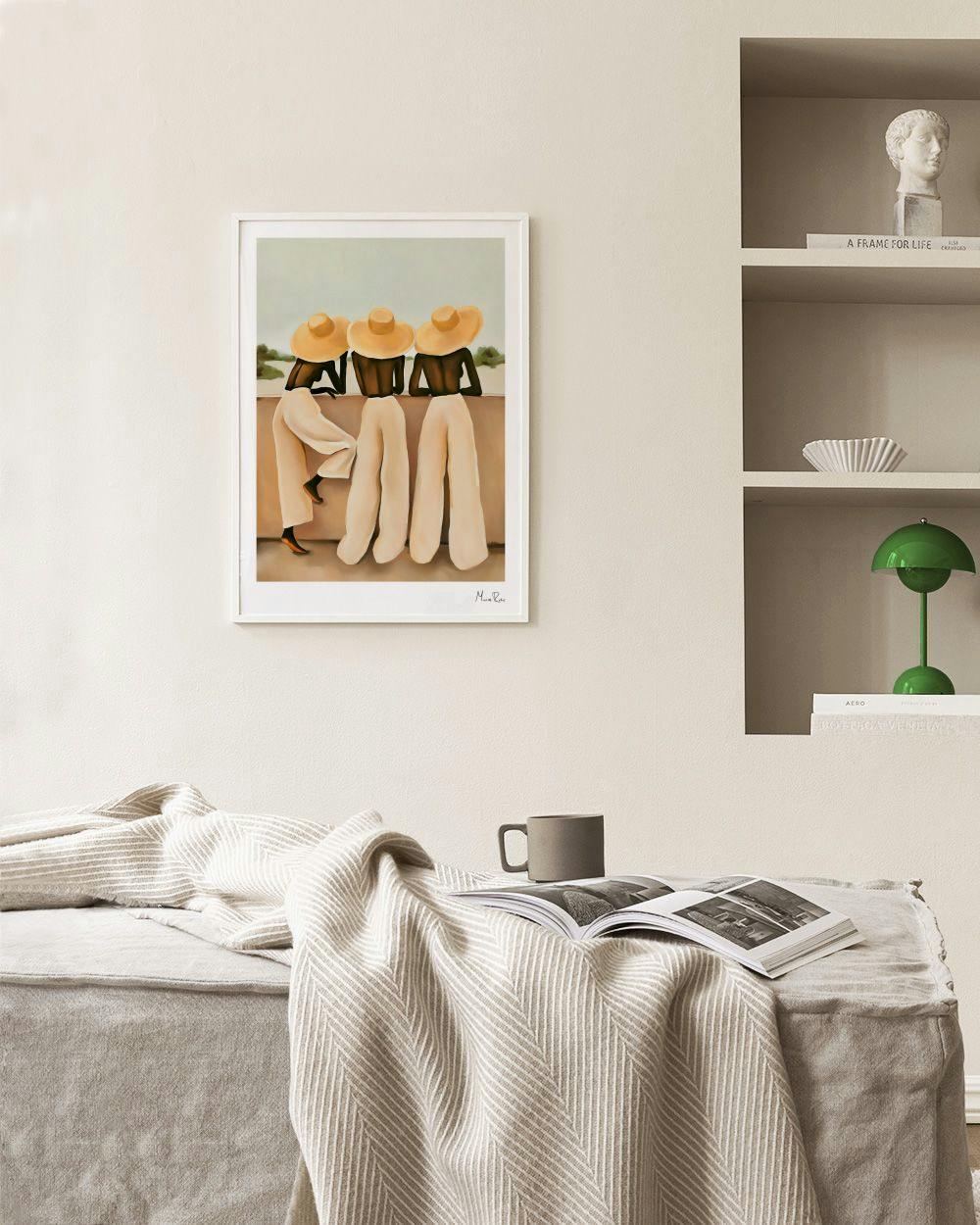 Affiche avec trois femmes aux chapeaux de paille et pantalons clairs, assises sur un mur, dans un salon beige.