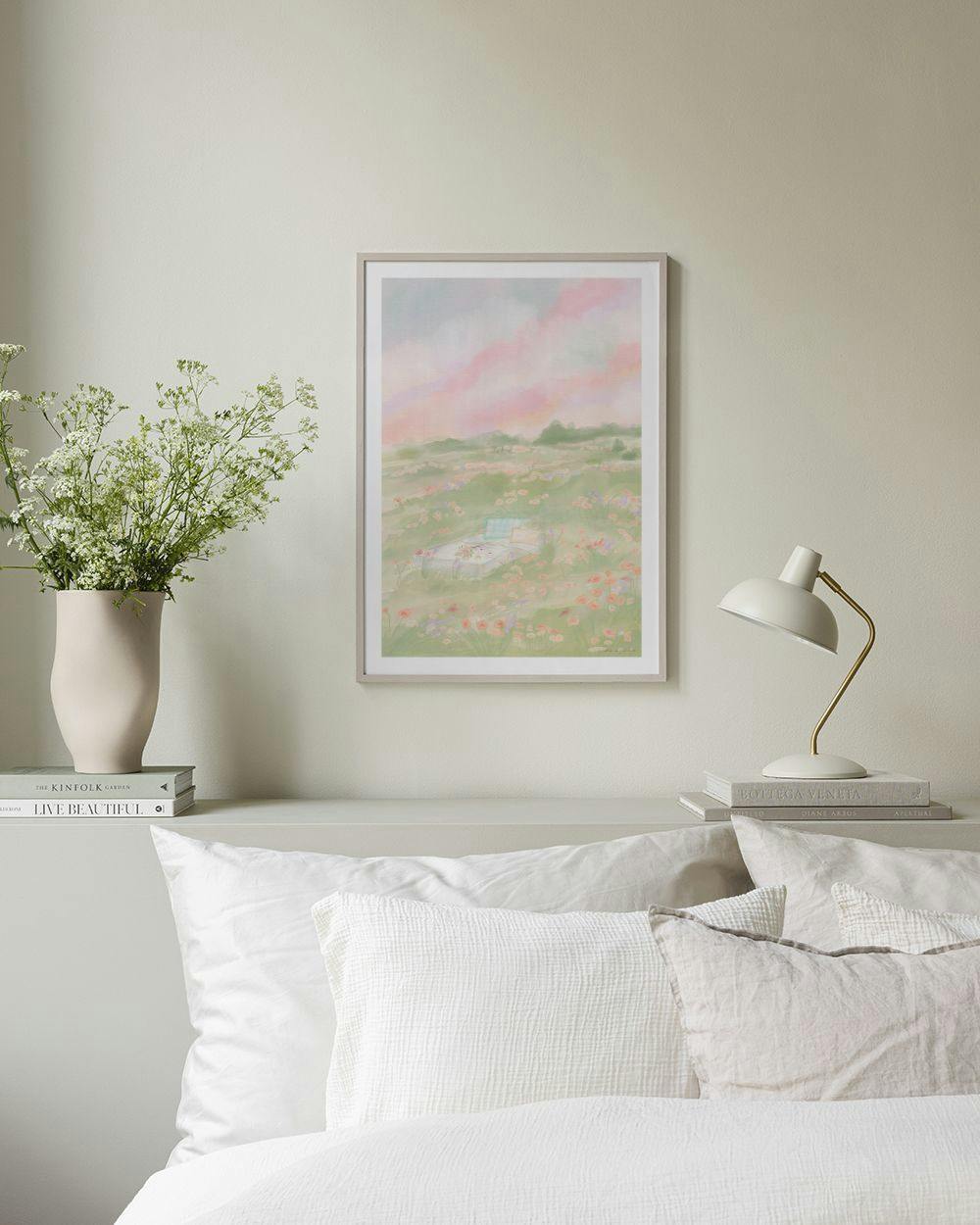 Affiche dun paysage fleuri avec ciel rose au coucher du soleil, affichée dans une chambre aux tons clairs.