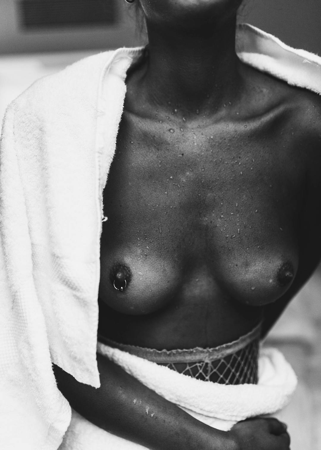 Affiche noir et blanc dune femme nue de la taille aux épaules, se séchant avec une serviette blanche, des gouttes deau sur la pe