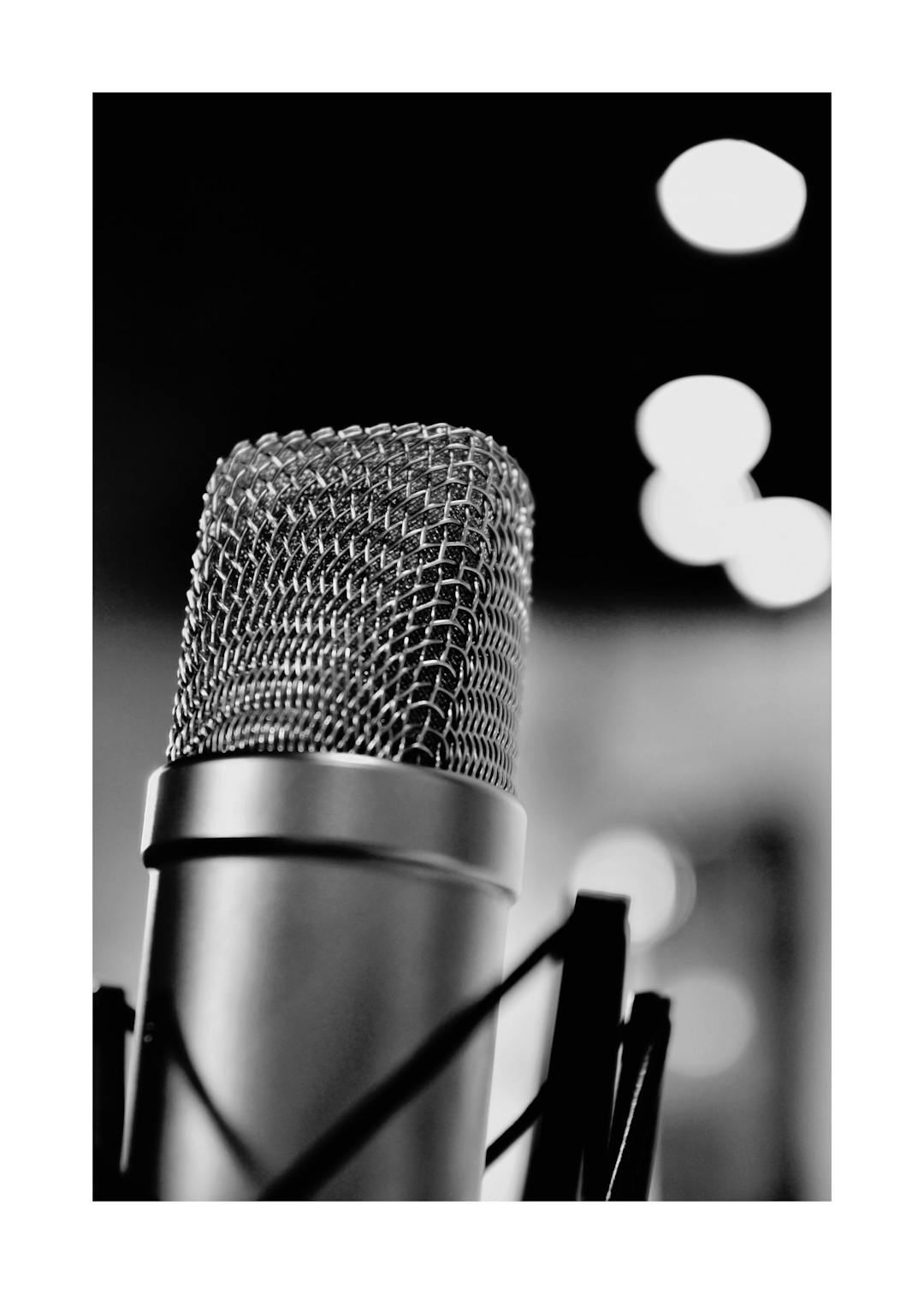 Affiche noir et blanc, gros plan dun microphone de studio, avec un effet bokeh en arrière-plan. Typographie sur laffiche.