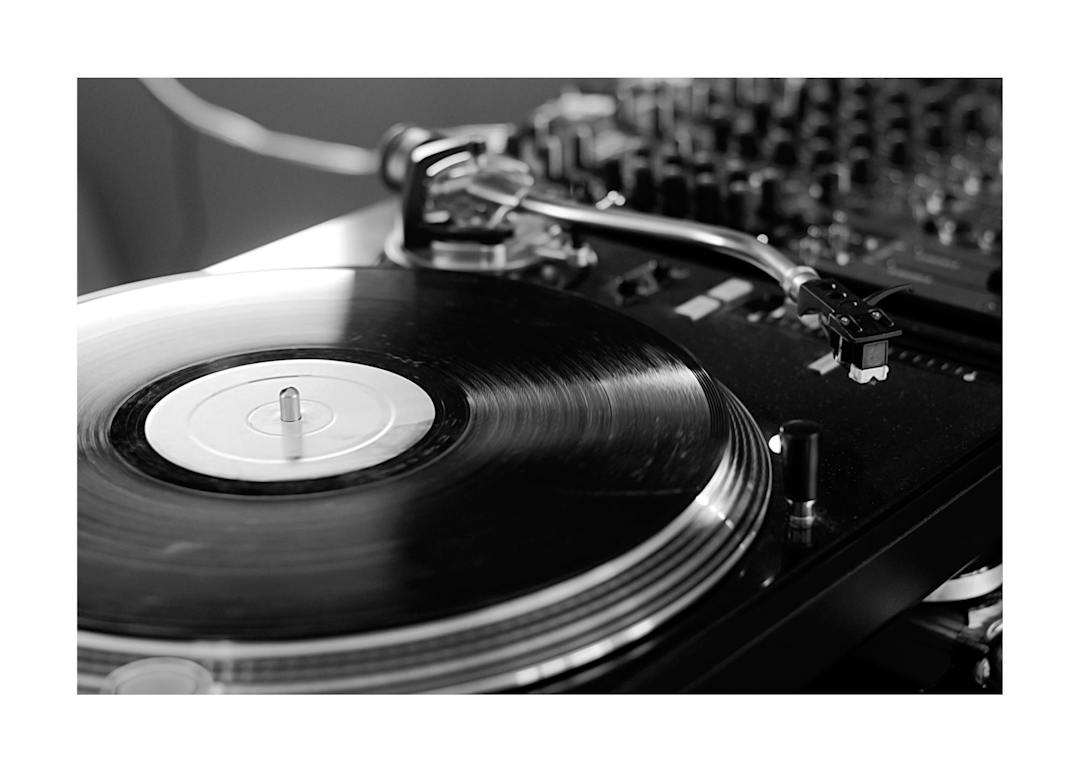 Affiche noir et blanc dun tourne-disque avec un disque vinyle et son bras, typographie sur bordure blanche.