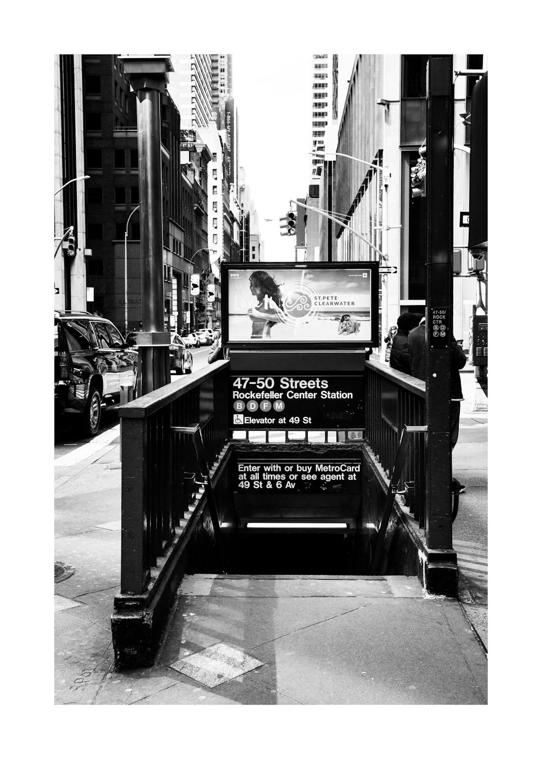 Affiche noir et blanc dune entrée de métro à New York, avec des gratte-ciel en arrière-plan.