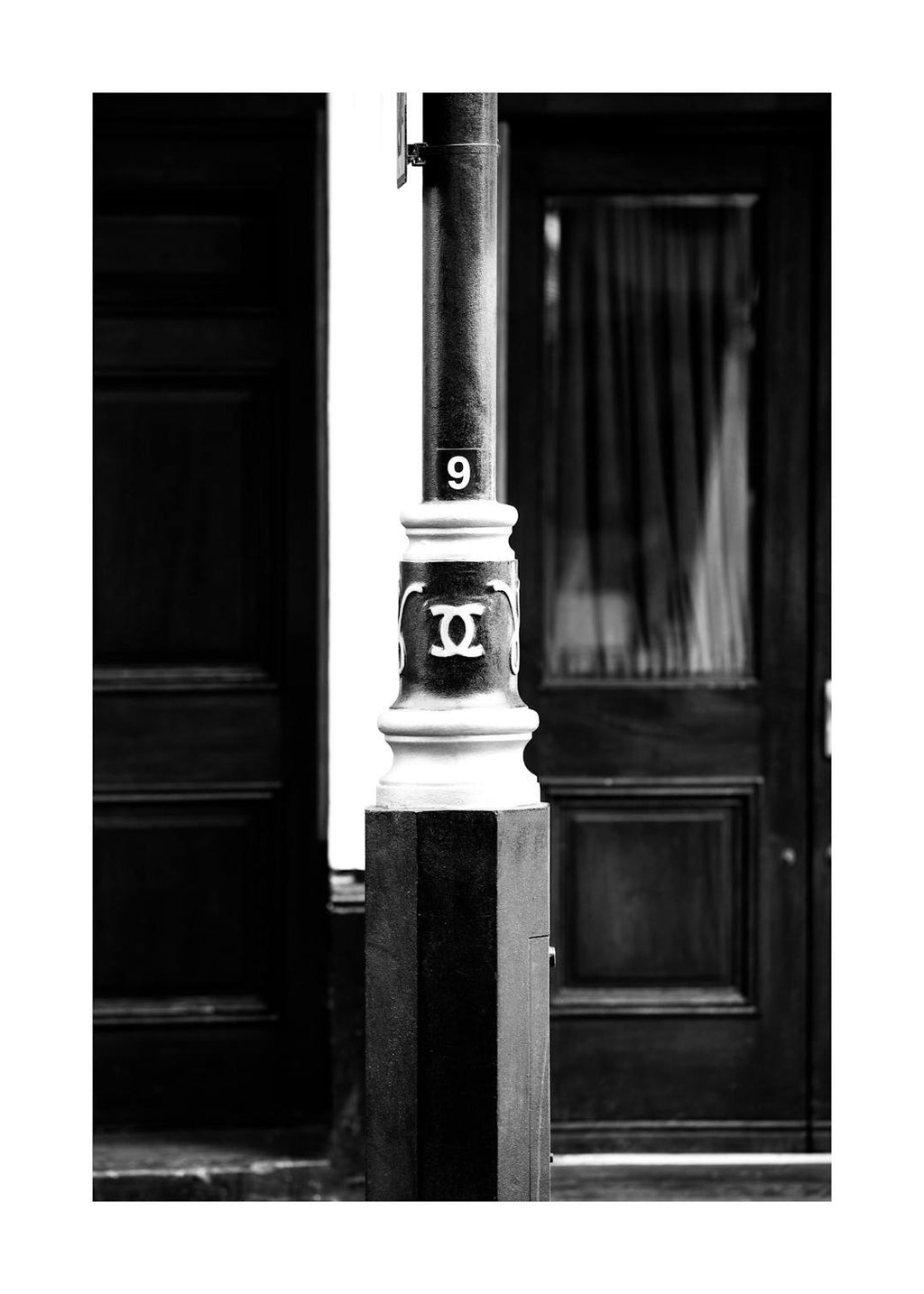 Affiche noir et blanc, lampadaire avec le logo CC et le chiffre 9, devant une porte sombre.