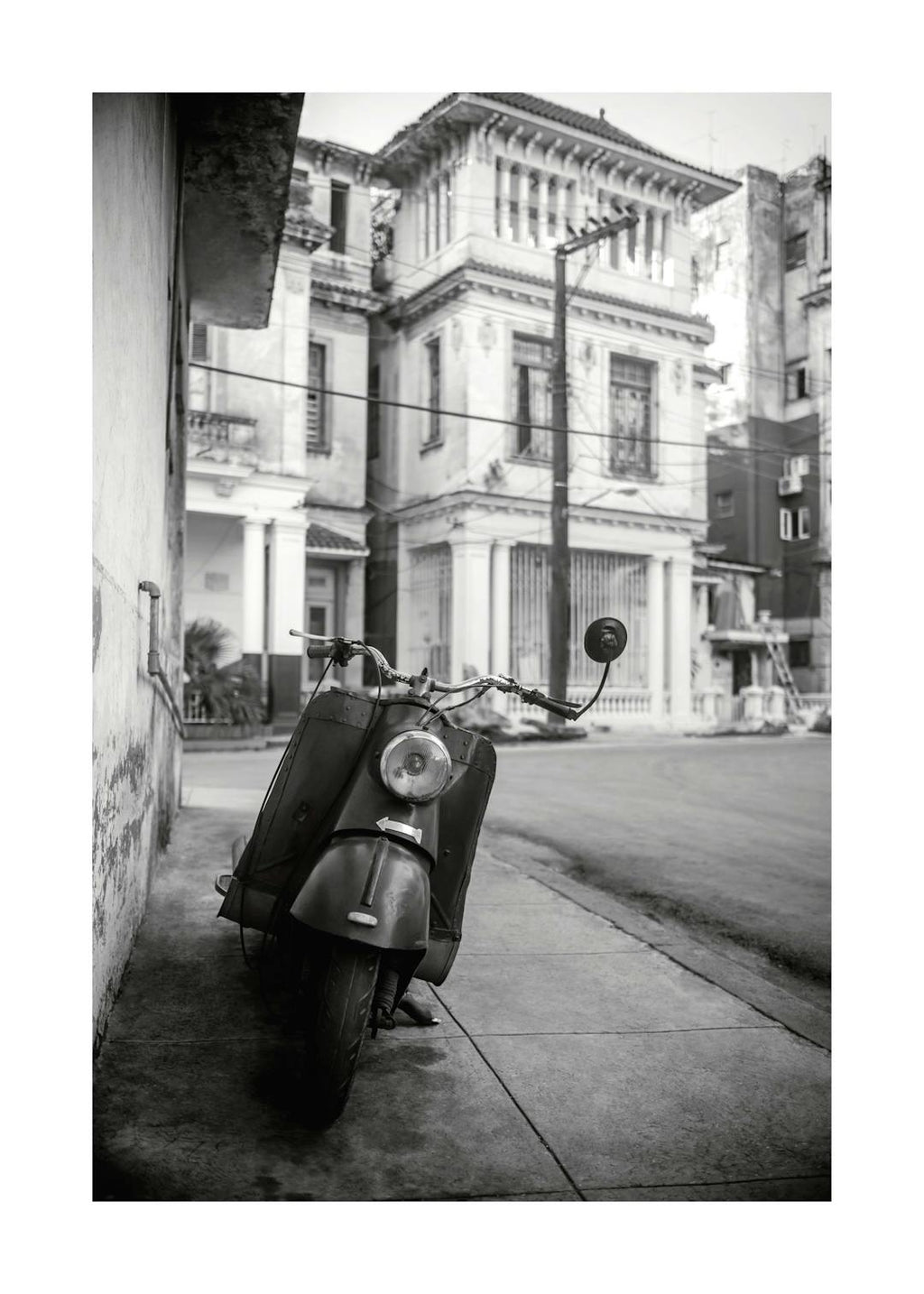Affiche noir et blanc dune Vespa garée dans une rue de La Havane avec des bâtiments en arrière-plan