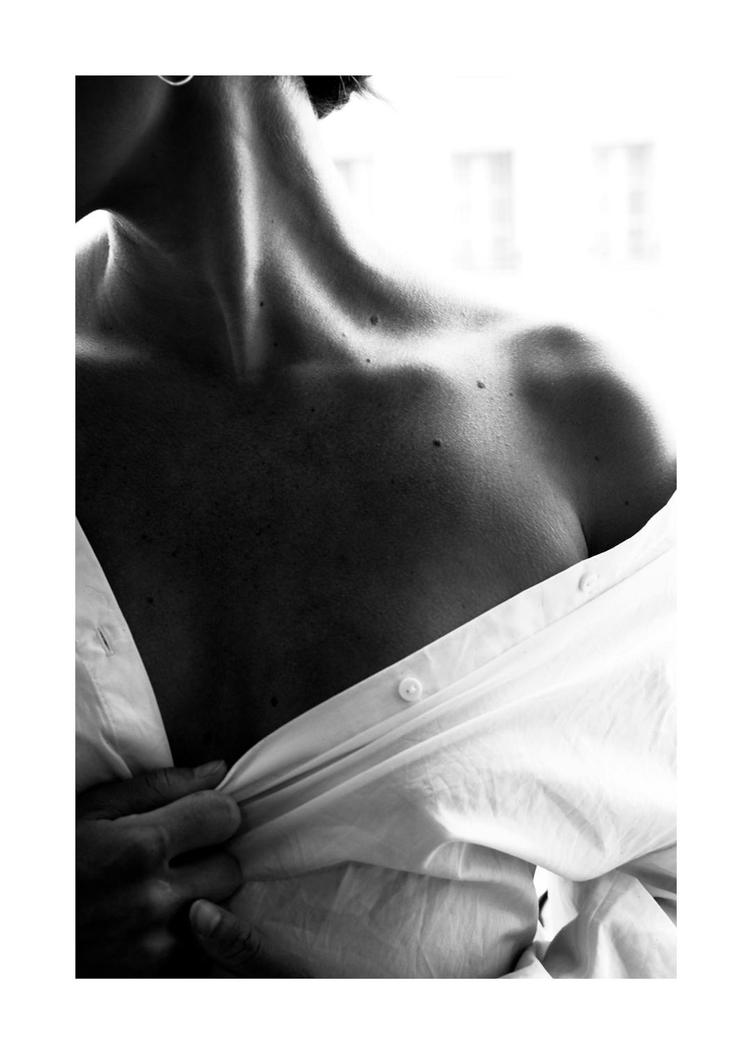 Affiche noir et blanc, photographie sensuelle dune femme dénudant son épaule et sa clavicule, chemise blanche ouverte.