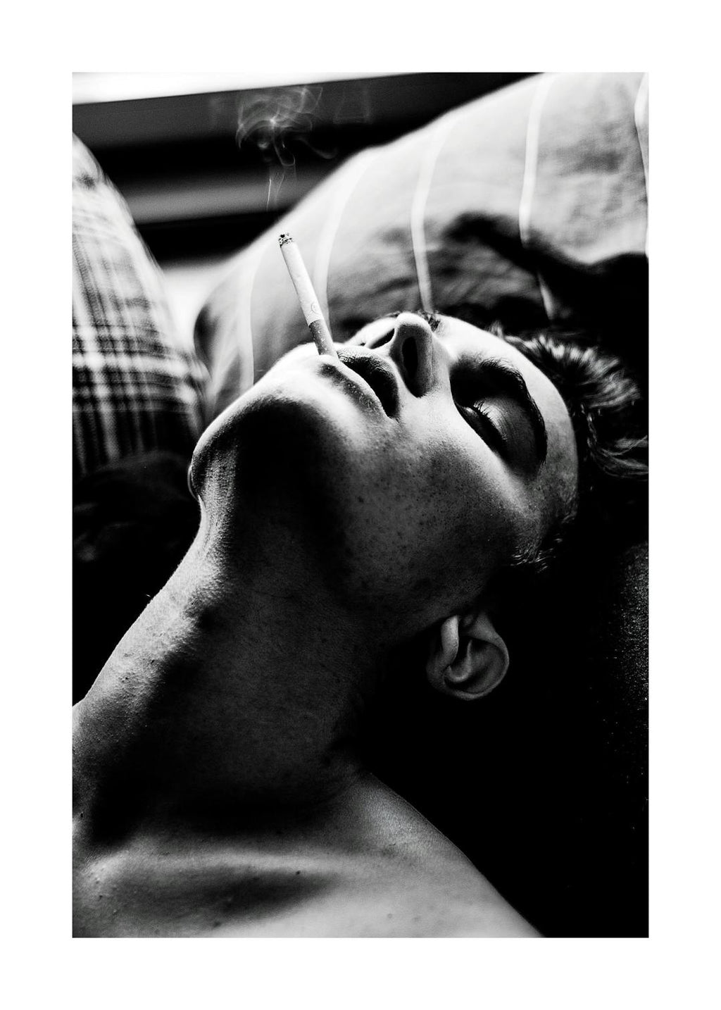 Affiche noir et blanc dun homme allongé fumant une cigarette, avec de la fumée sélevant de sa bouche