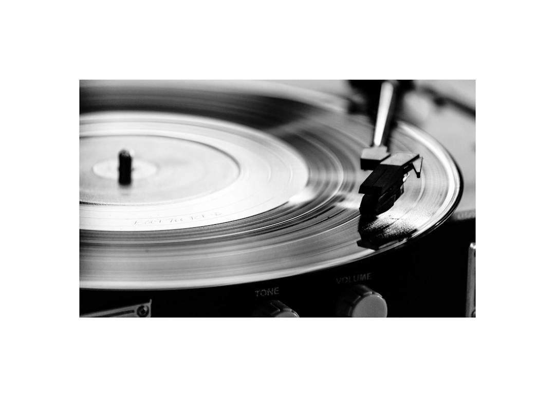 Affiche noir et blanc dune platine vinyle avec le bras de lecture et un disque, mettant en valeur les détails du sillon.