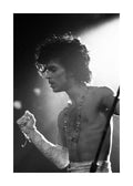 Affiche noir et blanc de Prince en concert, torse nu, cheveux bouclés, avec des perles et un gant en dentelle.