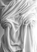 Affiche noir et blanc dun tissu fluide, drapé sur un corps, révélant des formes subtiles par transparence et reflets lumineux.