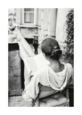 Affiche noir et blanc de femme lisant un livre, jambes levées, assise sur une chaise. Photographie de détente.
