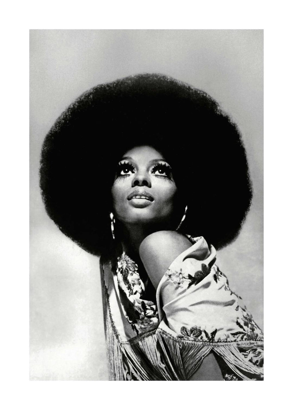 Affiche noir et blanc de Diana Ross avec une coiffure afro, regardant vers le haut, tenue à motifs et franges.