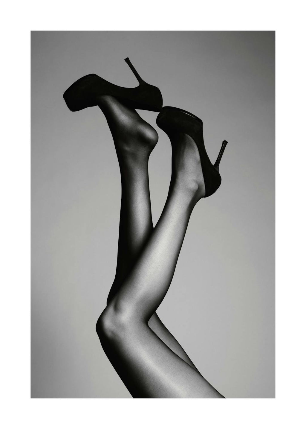 Affiche de photographie en noir et blanc de deux jambes tendues en lair avec des talons hauts noirs