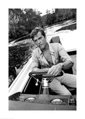 Affiche noir et blanc de Roger Moore conduisant un bateau avec une cigarette à la bouche, ambiance cinéma.