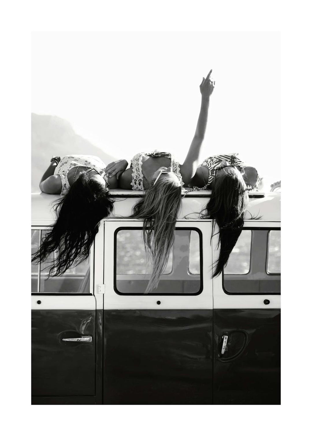 Affiche noir et blanc de trois jeunes filles allongées sur le toit dune fourgonnette, les cheveux flottant et le bras levé