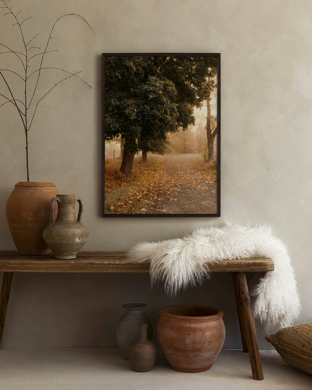 Affiche dun chemin de campagne bordé darbres en automne, affichée dans une pièce aux tons chauds.