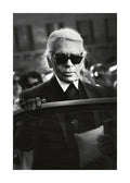 Affiche de Karl Lagerfeld en noir et blanc, avec lunettes de soleil et tenue sombre, tenant une portière de voiture