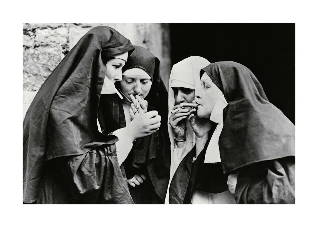 Affiche noir et blanc de quatre religieuses fumant, lune allumant la cigarette dune autre. Photographie iconique.
