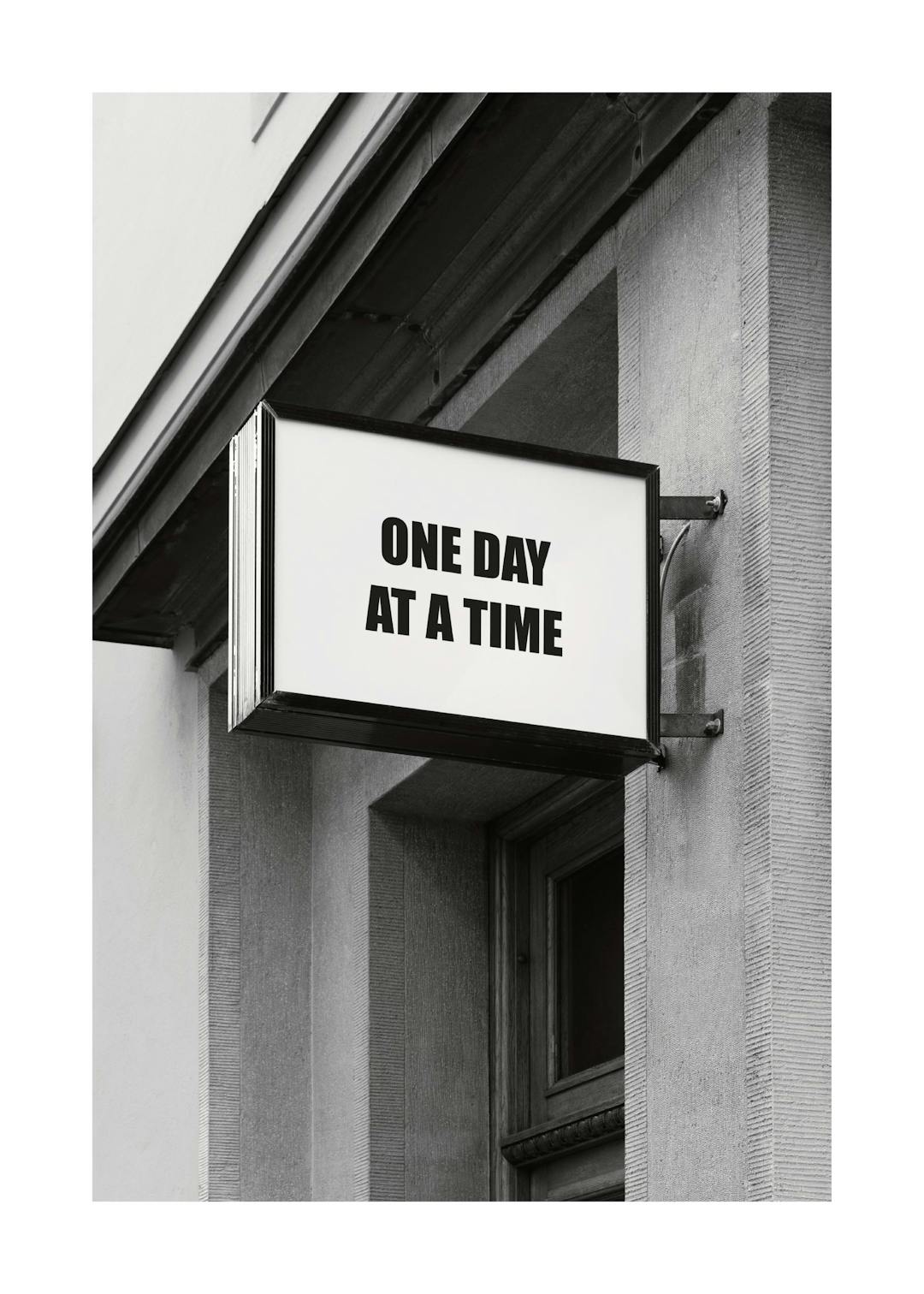Affiche noir et blanc dune enseigne sur un bâtiment avec le texte One Day at a Time, typographie noire.