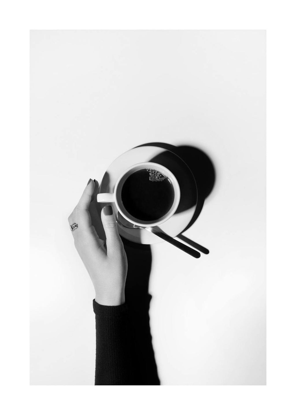Affiche noir et blanc avec une main féminine tenant une tasse de café, vue de dessus