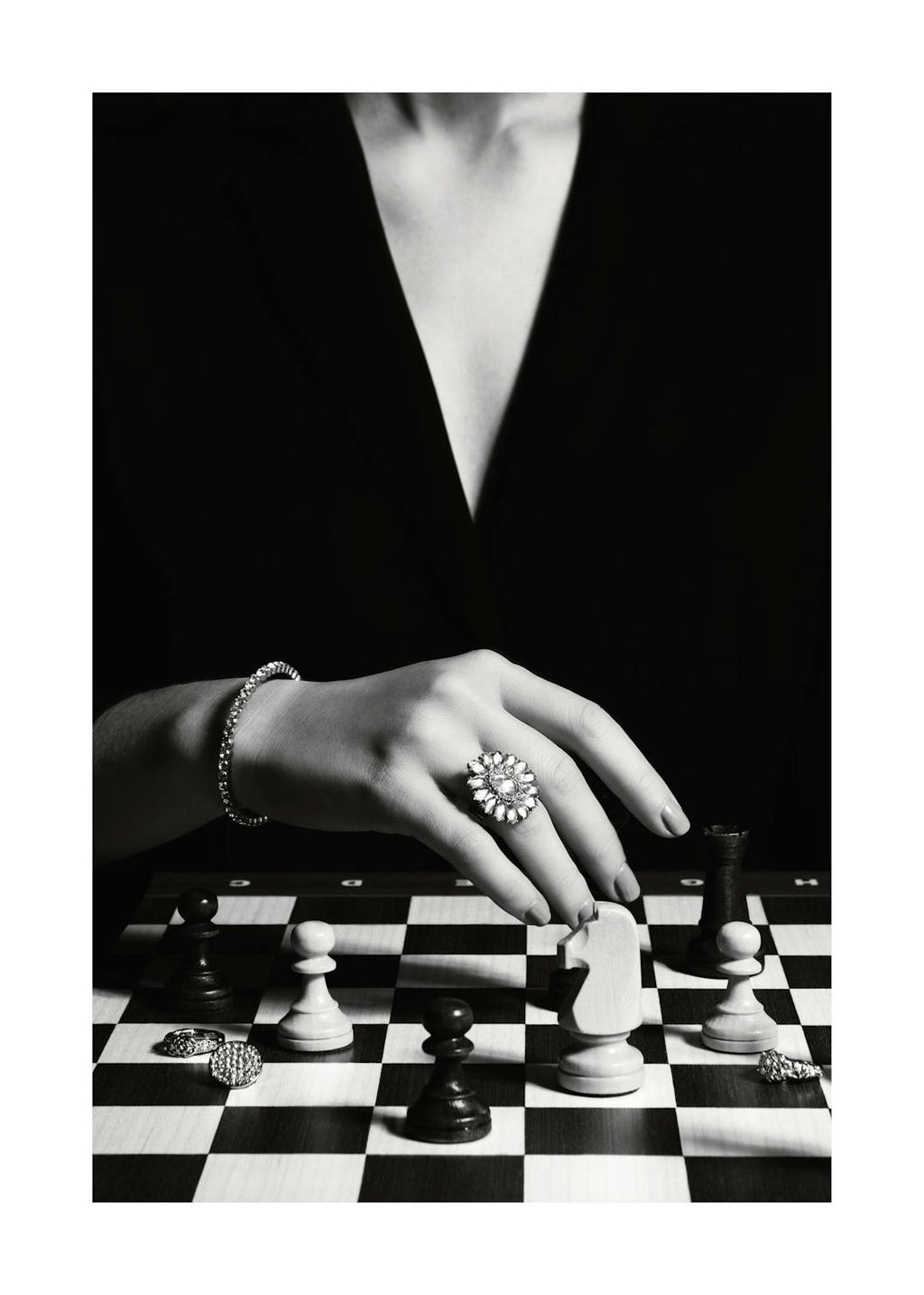 Affiche noir et blanc dune femme avec bague et bracelet jouant aux échecs sur un échiquier