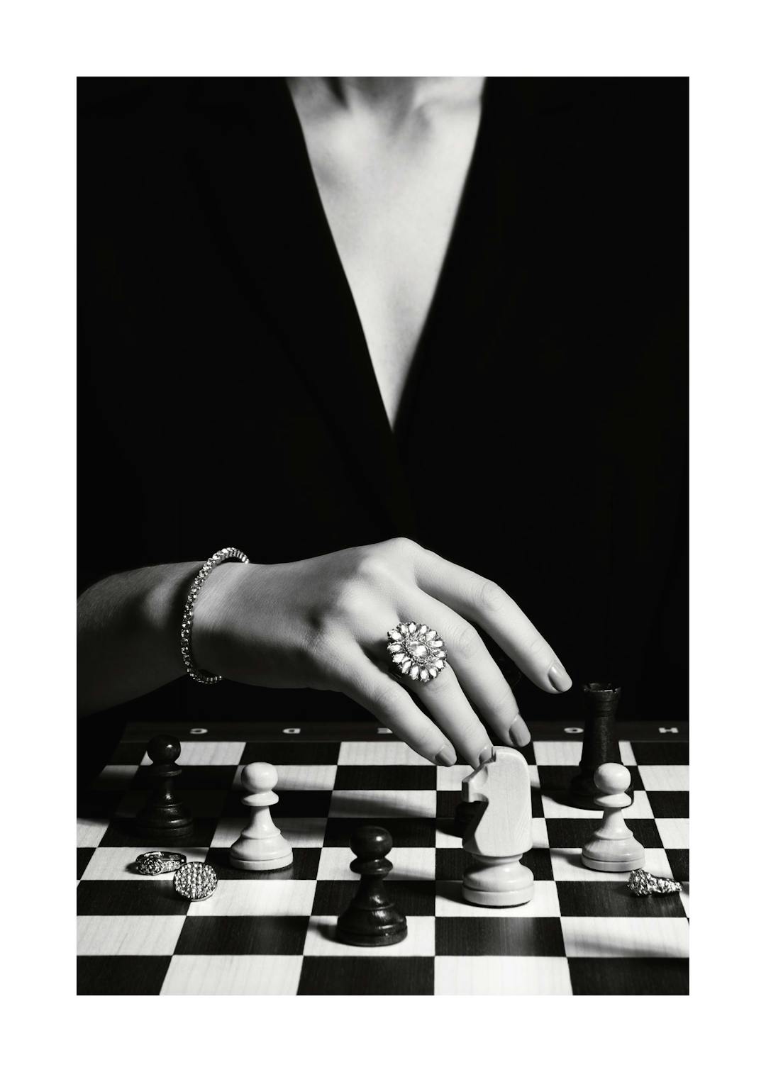 Affiche noir et blanc dune femme avec bague et bracelet jouant aux échecs sur un échiquier