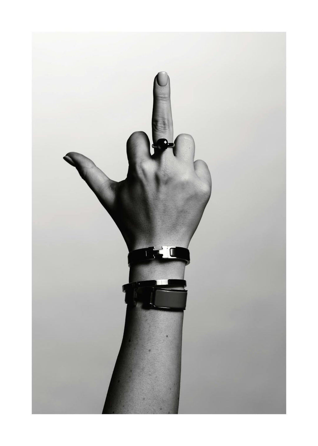 Affiche monochrome dune main faisant un doigt dhonneur, portant une bague noire et deux bracelets métalliques