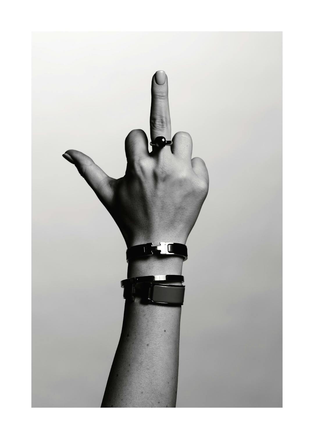 Affiche monochrome dune main faisant un doigt dhonneur, portant une bague noire et deux bracelets métalliques
