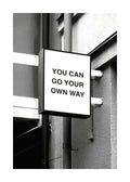 Affiche noir et blanc dun panneau carré avec le texte You can go your own way sur un mur dhabitation