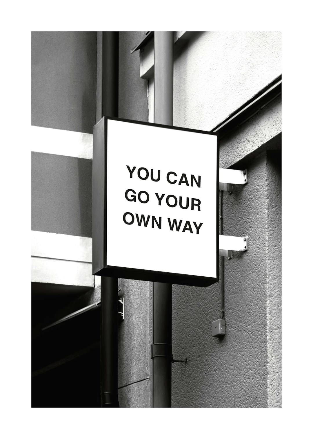 Affiche noir et blanc dun panneau carré avec le texte You can go your own way sur un mur dhabitation