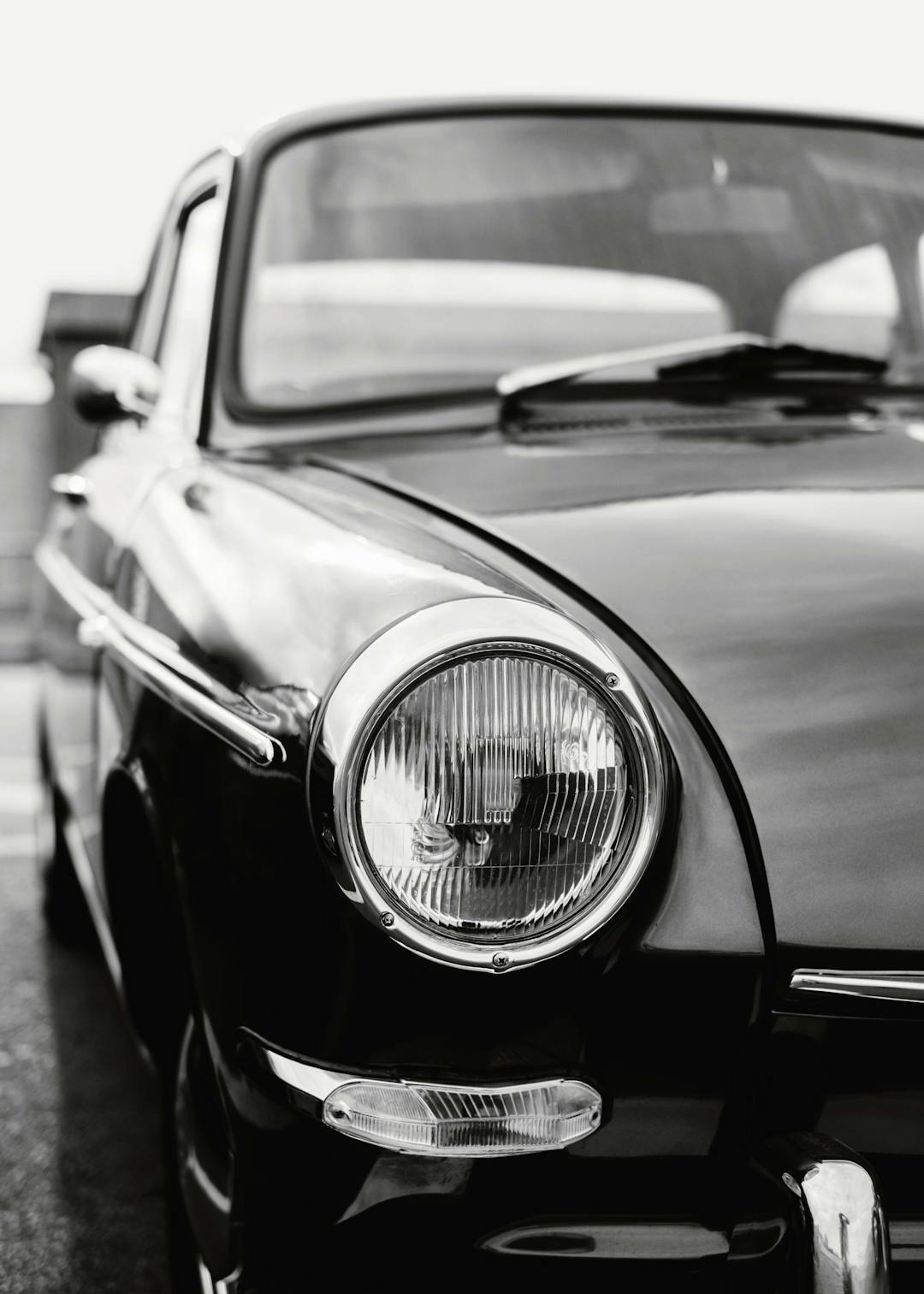 Affiche noir et blanc dune voiture classique avec un phare chromé en gros plan, ambiance vintage