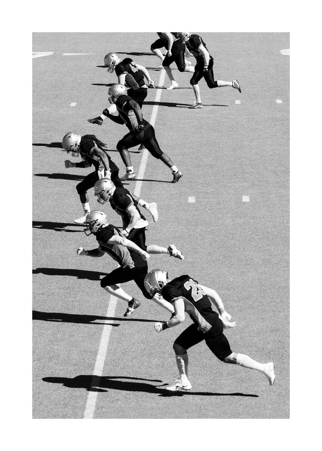 Affiche noir et blanc dune équipe de football américain en pleine course sur le terrain, illustrant le travail déquipe.