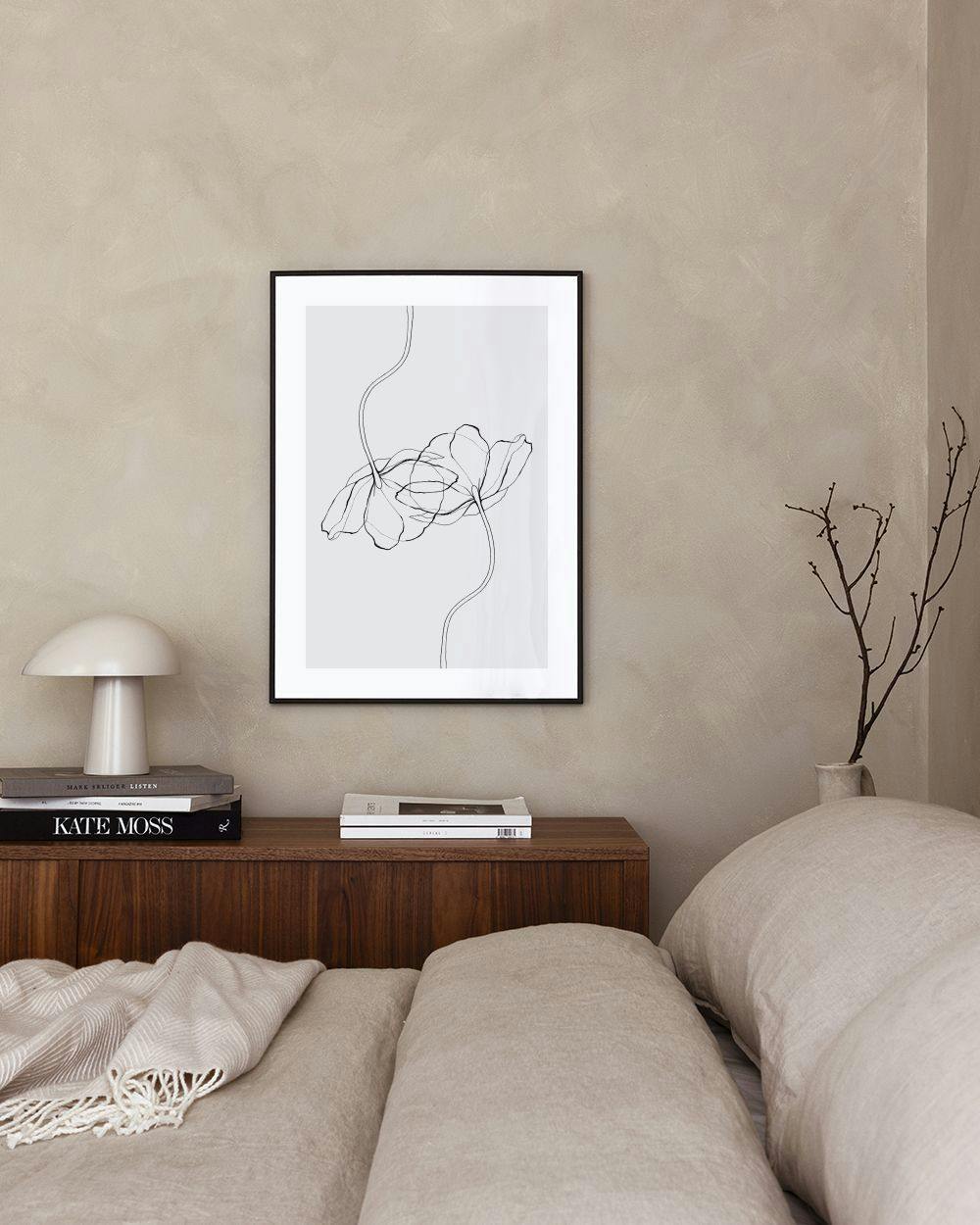 Affiche avec des fleurs dessinées au trait noir, suspendue au-dessus dun meuble blanc avec un vase gris, à côté dune porte.