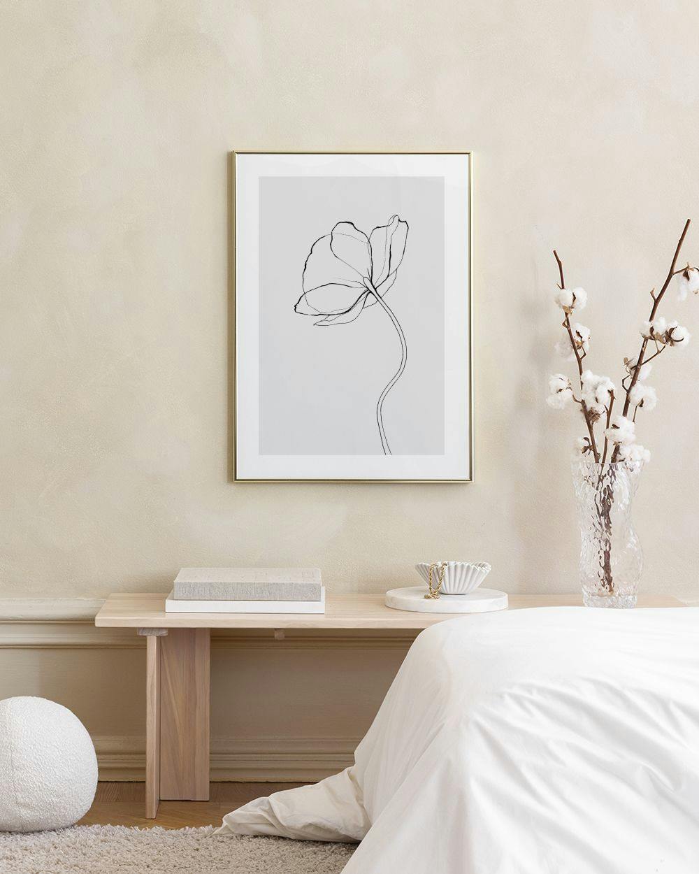 Affiche dune fleur noire aux contours délicats sur fond blanc, accrochée au mur dun salon moderne.
