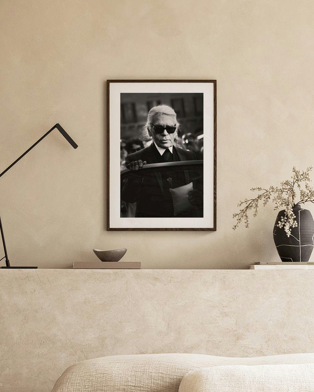 Affiche en noir et blanc de Karl Lagerfeld avec des lunettes de soleil, accrochée dans une pièce minimaliste.