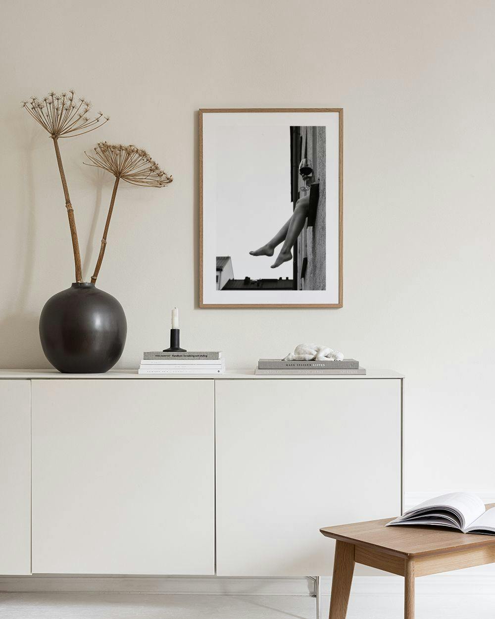 Affiche photo noir et blanc de jambes féminines sortant dune fenêtre avec un verre de vin, dans un salon moderne.