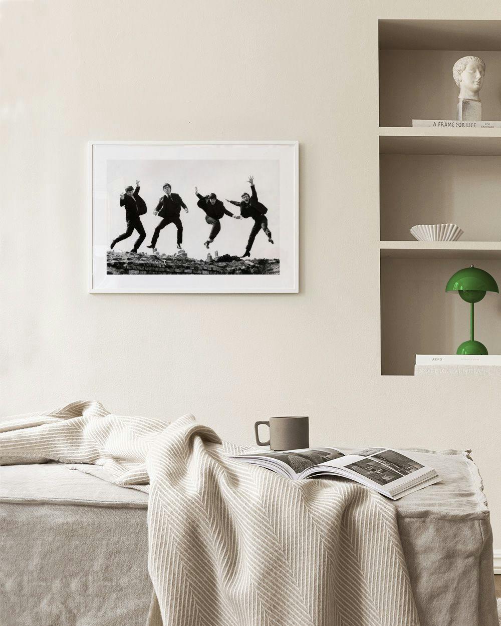 Affiche noir et blanc des Beatles sautant en lair, affichée dans un salon moderne.