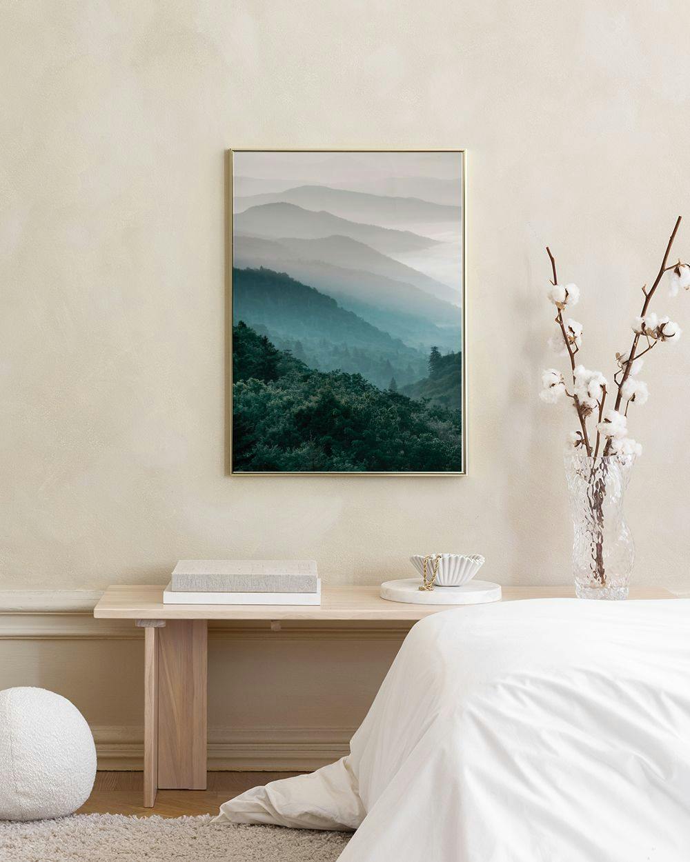 Affiche de montagnes brumeuses aux teintes bleues et vertes, suspendue au-dessus dun meuble bleu.
