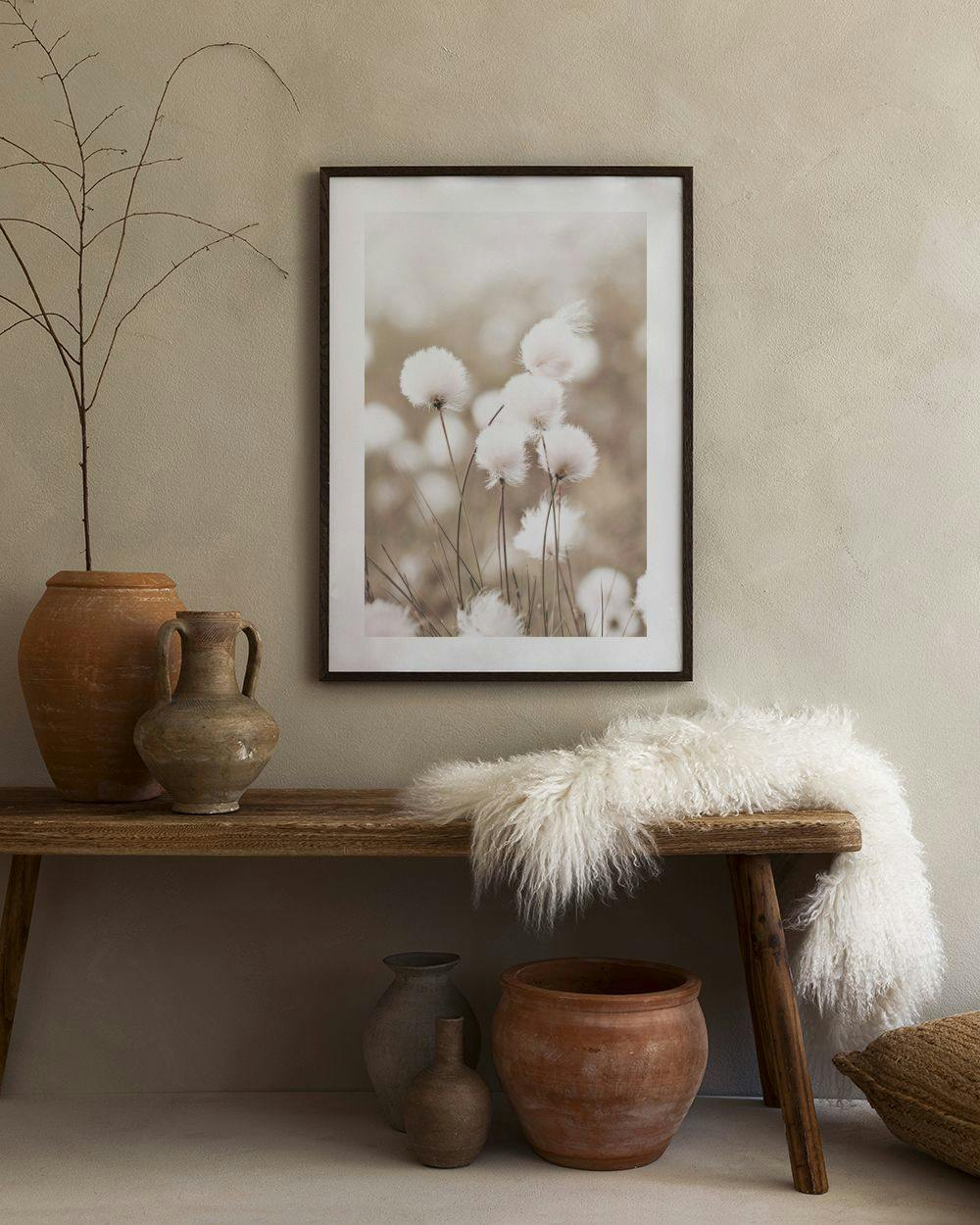 Affiche de fleurs de coton duveteuses et blanches, suspendue au-dessus dun buffet blanc avec des vases décoratifs.