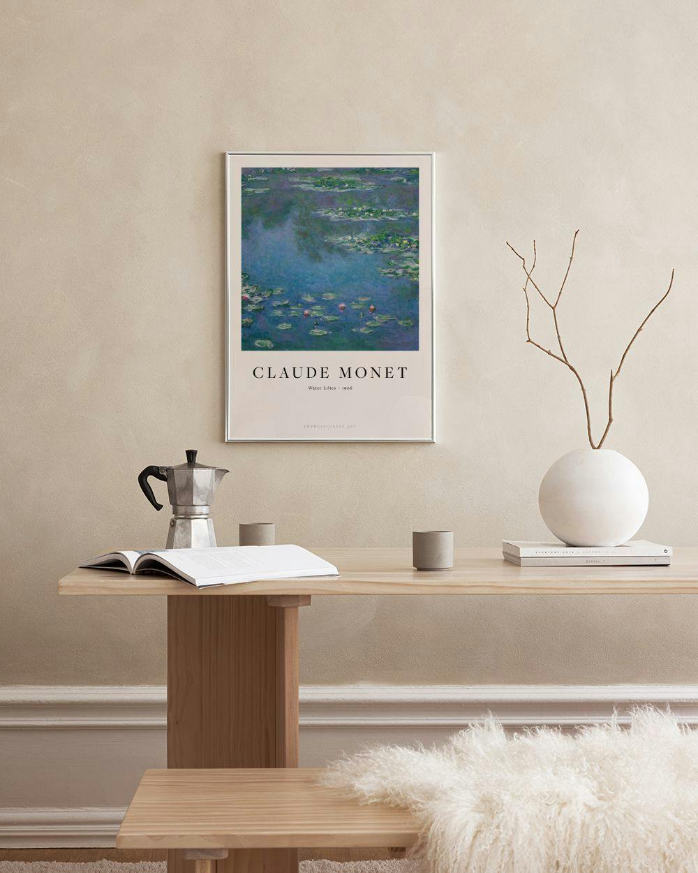 Affiche de Monet, Les Nymphéas, sur un mur gris, au-dessus dun meuble bas blanc avec des vases et des livres.