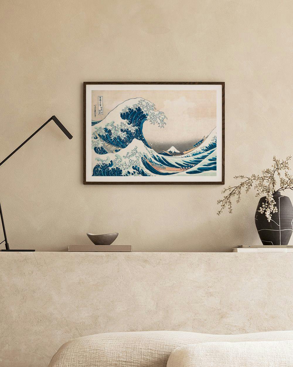Affiche de la Grande Vague de Kanagawa, accrochée au-dessus dune table basse grise dans un salon moderne.