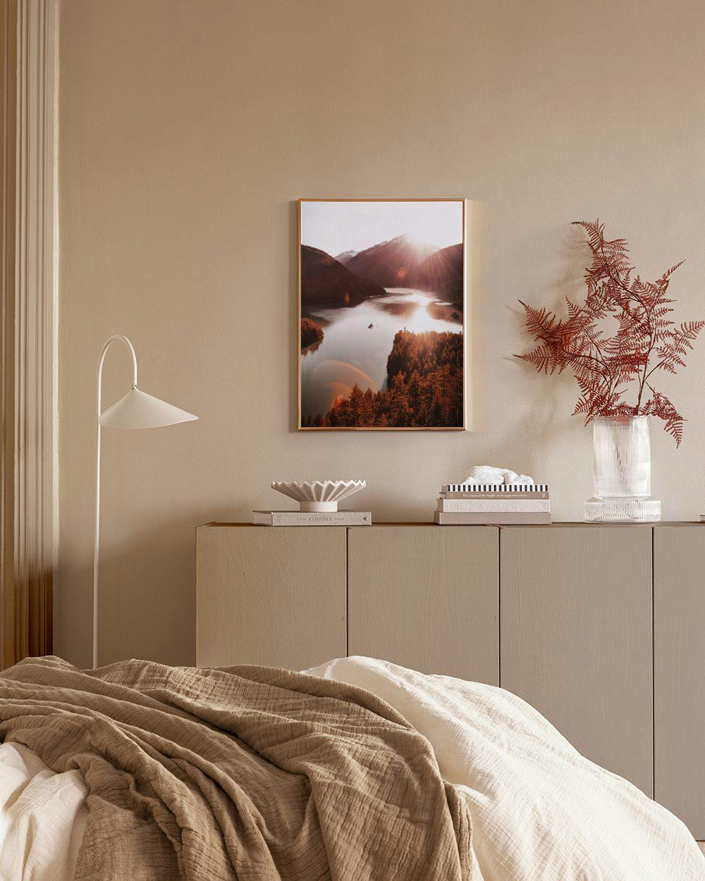 Affiche lac de montagne au coucher du soleil, avec arbres et reflets, accrochée au-dessus dun meuble blanc et dune chaise en cui