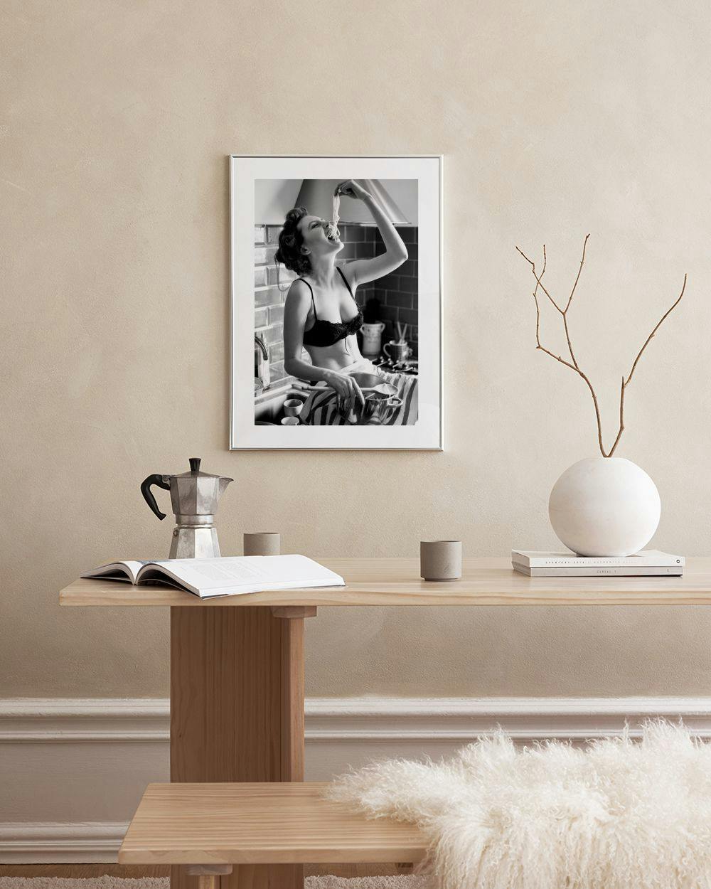 Affiche en noir et blanc dune femme mangeant des spaghettis dans une cuisine, accrochée dans un salon moderne.