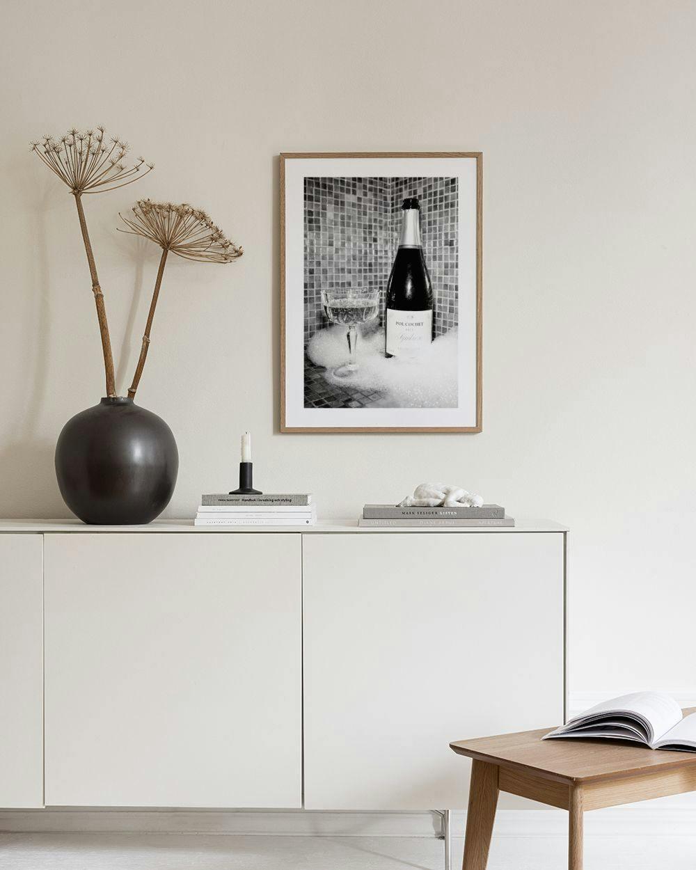 Affiche noire et blanche dune bouteille de champagne et dune coupe dans un bain moussant, affichée dans un salon moderne.