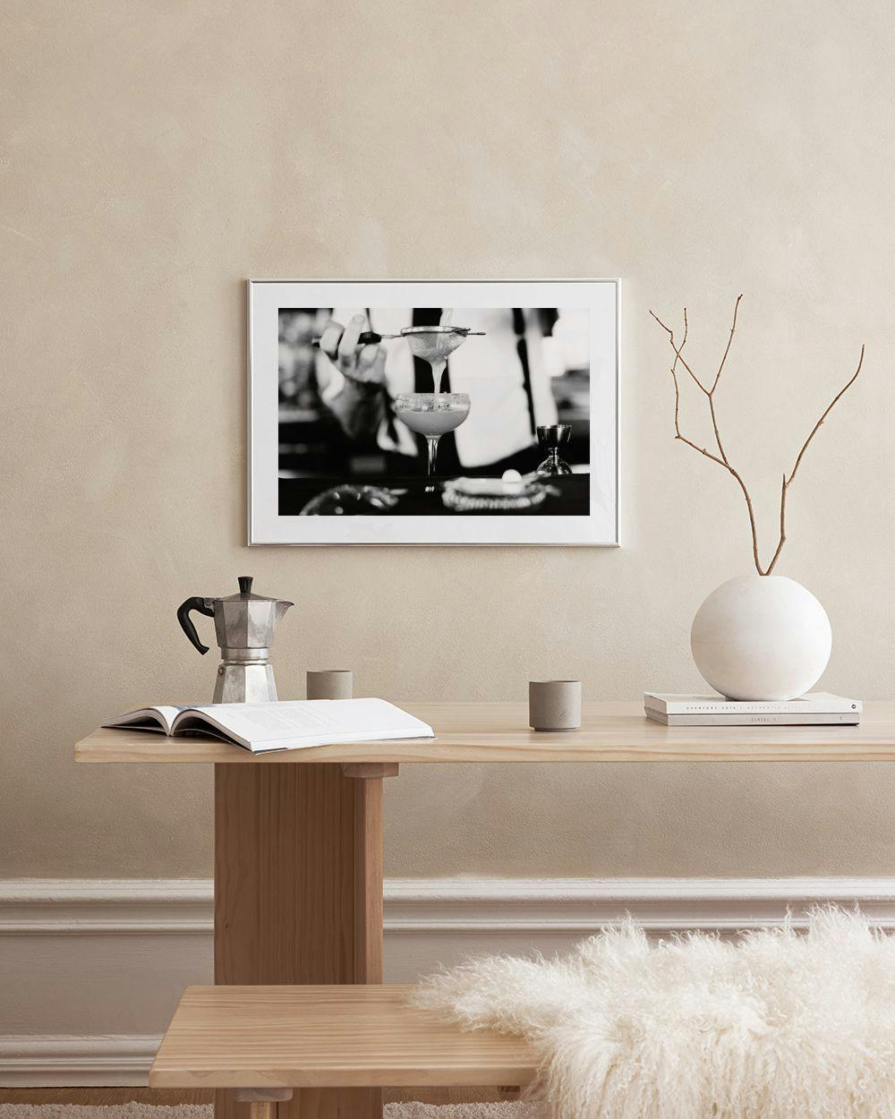 Affiche noir et blanc dun barman préparant un cocktail, accrochée dans un salon moderne.