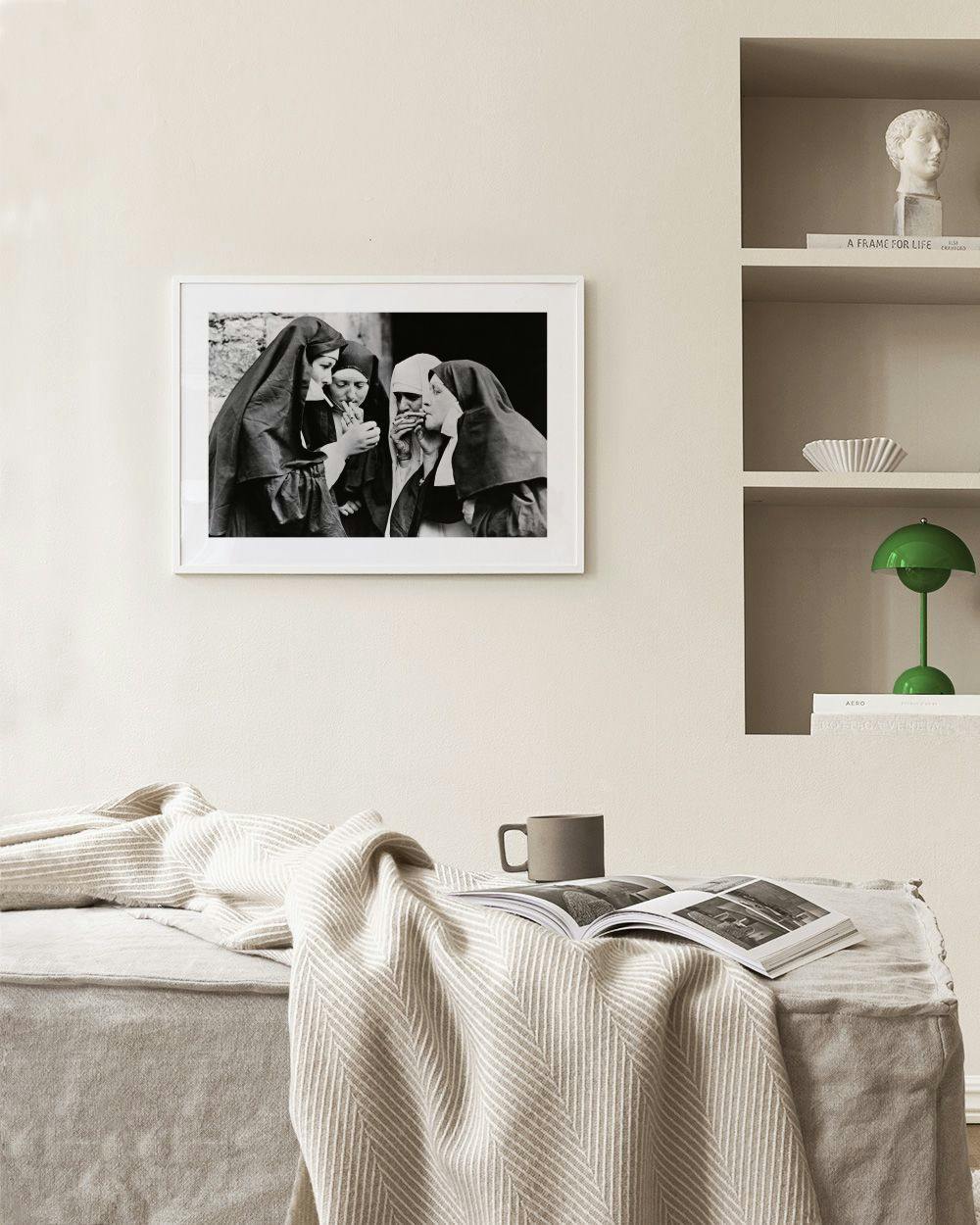 Affiche en noir et blanc de cinq nonnes avec un briquet, accrochée dans un salon moderne.