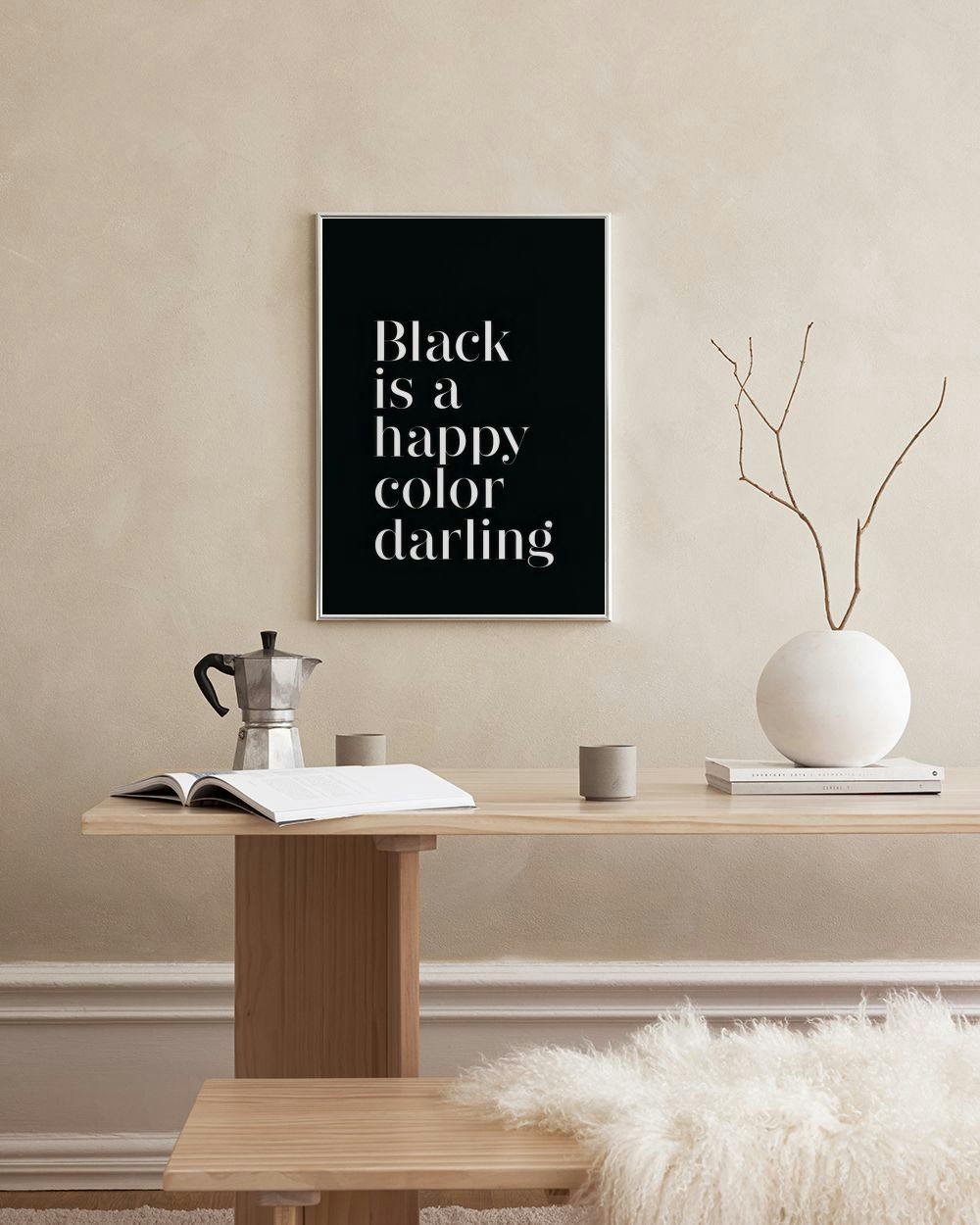 Affiche noire avec le texte blanc Black is a happy color darling, exposée dans un salon moderne.